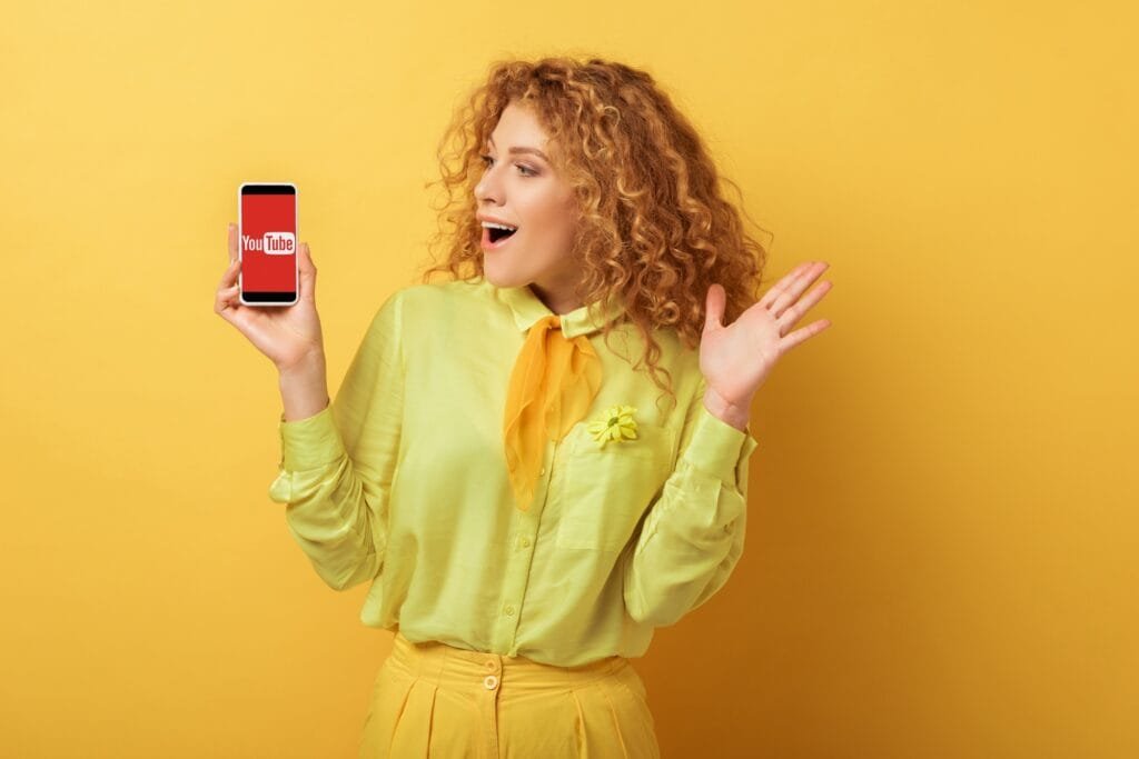 KYIV, UKRAINE - FEBRUARY 4, 2020: excited redhead woman looking at smartphone with youtube app on